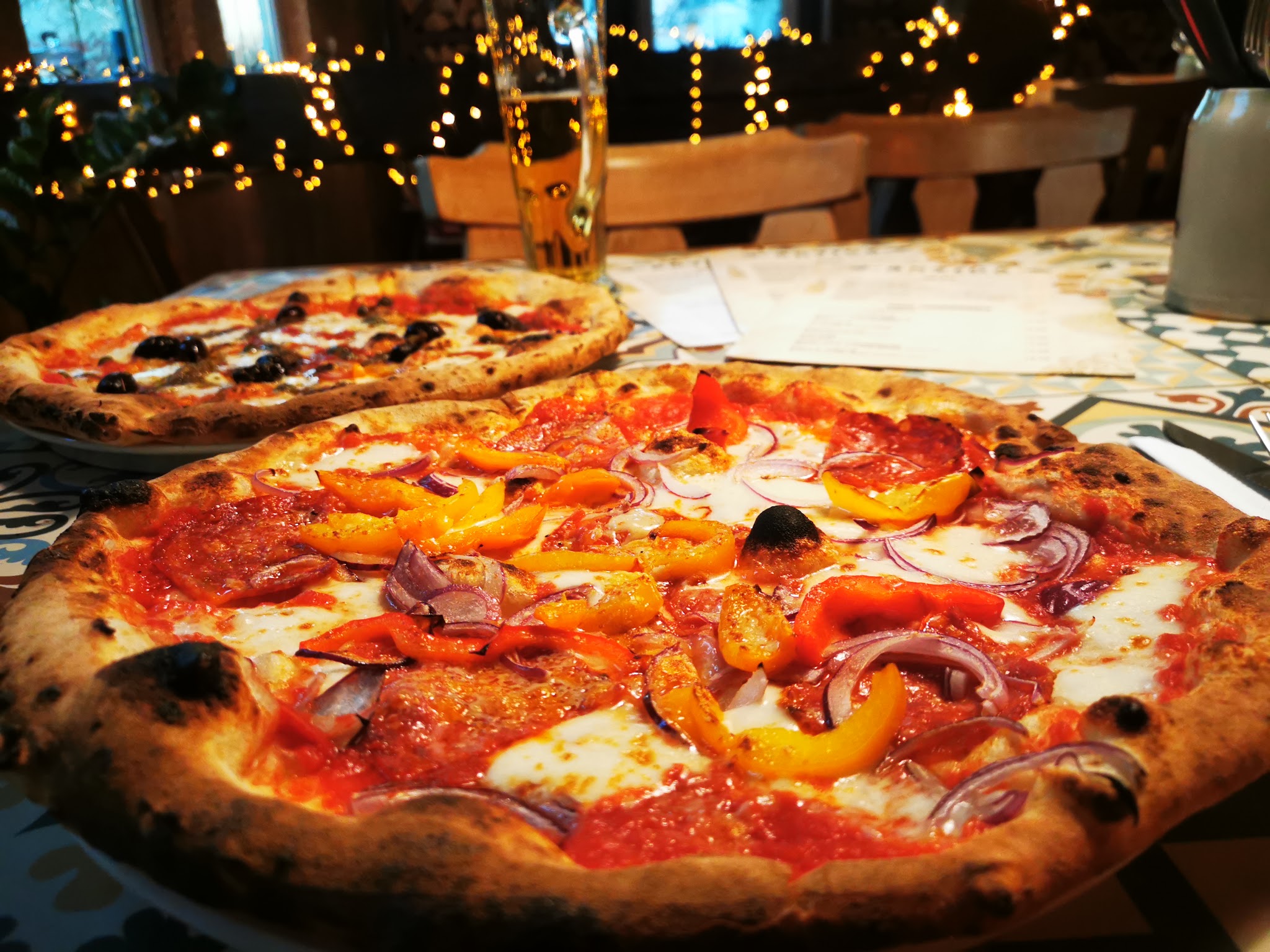 Gedeckter Tisch mit Pizza und Lichterketten im Gastraum